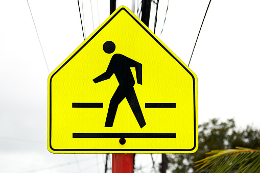 Close-up of a bright yellow square walkway street signage photographed against a cloudy sky, seen in the Philippines, Asia