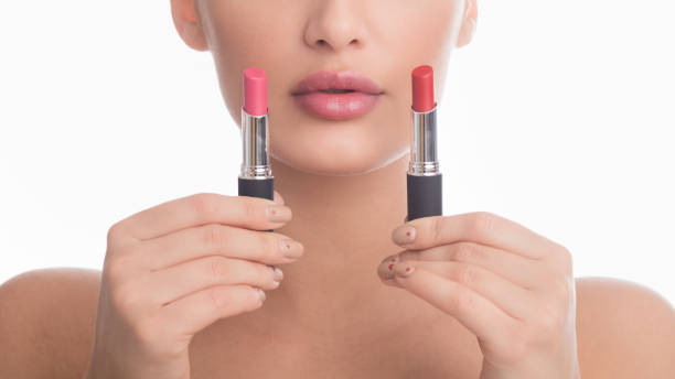 istock Difficult choice. Girl holding two lipsticks, white background 1206010006