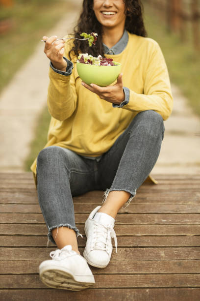 istock Unrecognizable person eating salad in public park 1206020606