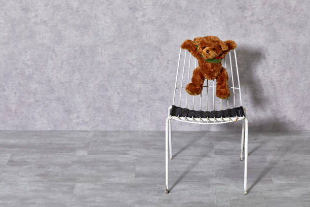 White metal chair and teddy bear on gray background