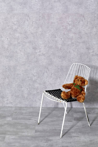istock White metal chair and teddy bear on gray background 1206020749