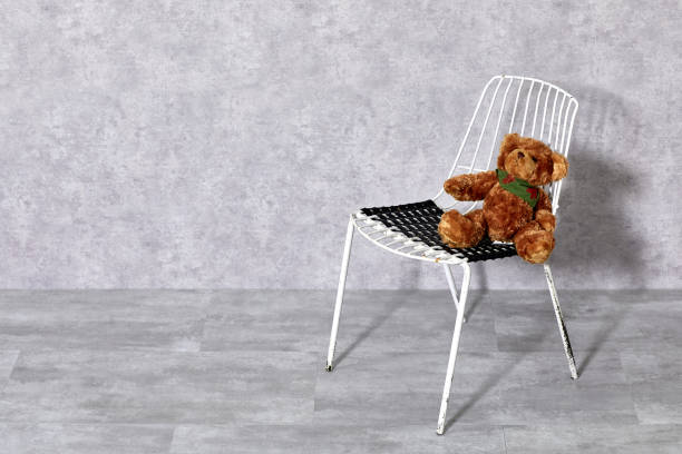 White metal chair and teddy bear on gray background