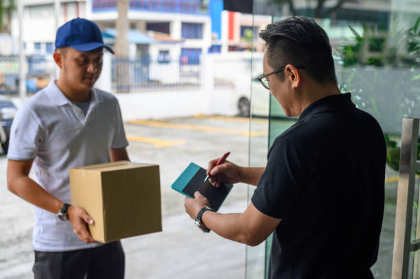 istock Asian delivery man smiling while holding a cardboard box delivery to his customer. 1206021262