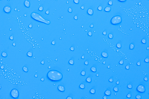 Close up of water drops on blue sky tone background. Abstract blue wet texture with bubbles on plastic PVC surface or grunge. Realistic pure water droplets condensed. Detail of canvas leather texture