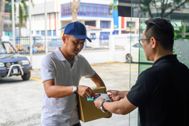 istock Asian delivery man smiling while holding a cardboard box delivery to his customer. 1206021358