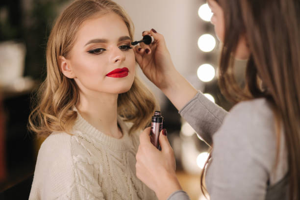 istock Makeup artist work in beauty studio. Woman applying by professional make up master. Beautiful make up artist make a makeup for blond hair model 1206021967