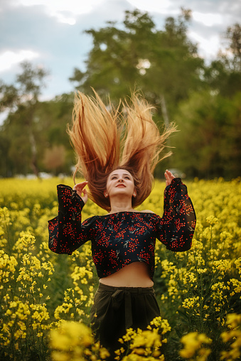 Hermosa mujer tirándose el pelo en el campo de la colza photo
