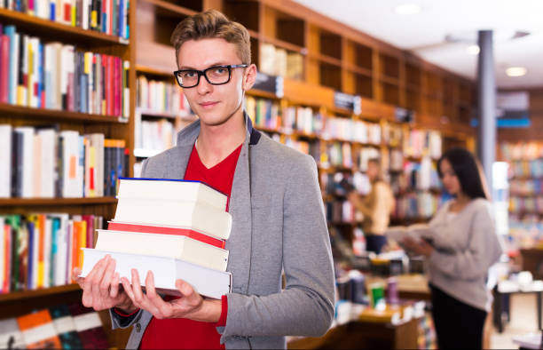 istock student standing in library with pile of books 1206028379