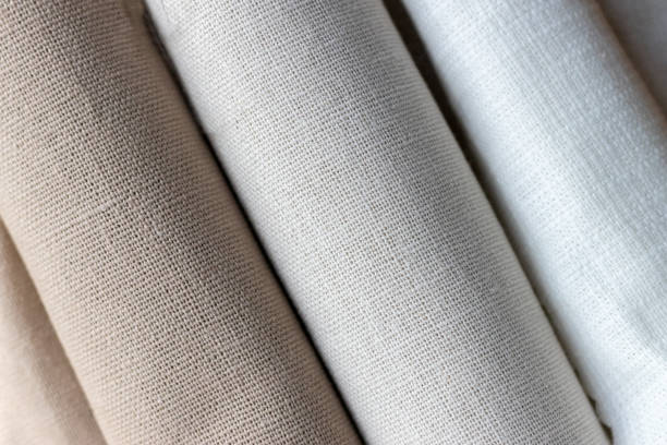 Diagonal textural background of three types of natural linen fabric, rolled up. Selective focus. Closeup view Diagonal textural background of three types of natural linen fabric, rolled up. Selective focus. Closeup view textile industry textile thread industry stock pictures, royalty-free photos & images