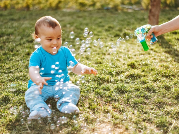 Baby boy playing with soap bubbles Baby boy playing with soap bubbles baby gun stock pictures, royalty-free photos & images