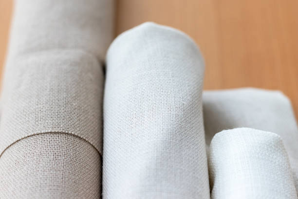 istock Three rolls of natural linen fabric in different colors on a wooden table. Selective focus. Closeup view. Blurred background 1206030152