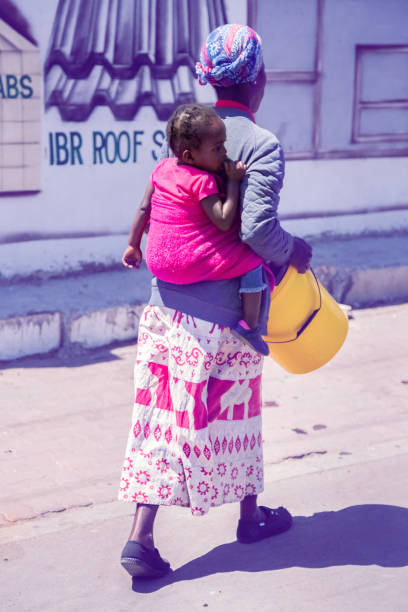 frauen tragen ihr kind mit einem tuch auf dem rücken. - soccer city stock-fotos und bilder