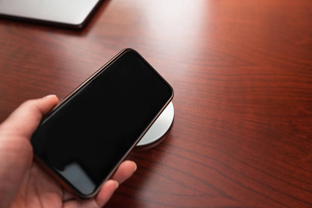 istock Hand holds a mobile smart phone for charging wirelessly by sharing battery via device. 1206032725