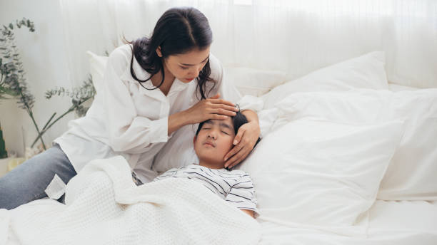 Young Asian mother hand take care and checking her son fever temperature, sick boy sleeping in bed, woman worried of corona influenza, medical healthcare and prevent epidemic disease flu virus concept joven mano madre asiática cuidar y comprobar la temperatura de la fiebre de su hijo, niño enfermo durmiendo en la cama, mujer preocupada por la gripe corona, atención médica y prevenir el concepto de virus de la gripe de la enfermedad epidémica