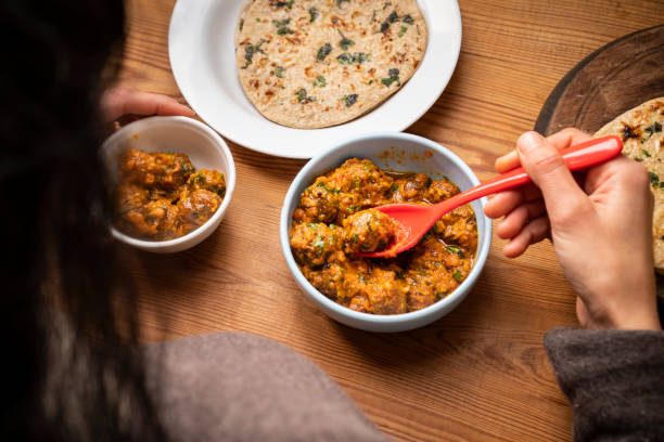 istock Woman having food, Potato curry (Kashmiri dum aloo) with chapatti (roti) on table. 1206034210