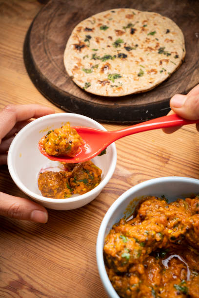 istock Woman having food, Potato curry (Kashmiri dum aloo) with chapatti (roti) on table. 1206034221