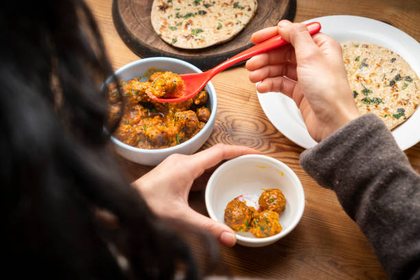 istock Woman having food, Potato curry (Kashmiri dum aloo) with chapatti (roti) on table. 1206034287