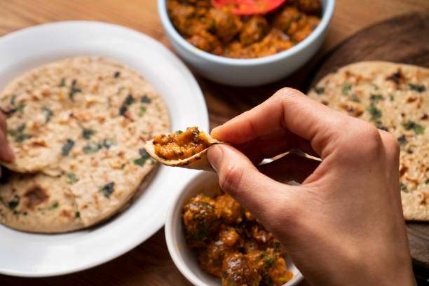 istock Woman having food, Potato curry (Kashmiri dum aloo) with chapatti (roti) on table. 1206034405
