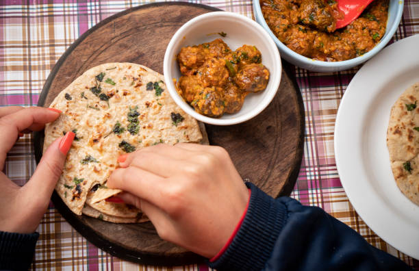 istock Woman having food, Potato curry (Kashmiri dum aloo) with chapatti (roti) on table. 1206034484