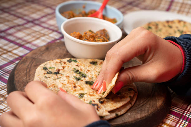 istock Woman having food, Potato curry (Kashmiri dum aloo) with chapatti (roti) on table. 1206034604