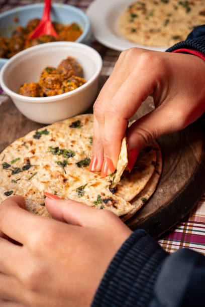 istock Woman having food, Potato curry (Kashmiri dum aloo) with chapatti (roti) on table. 1206034945