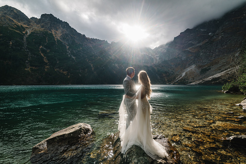 The bride and groom near the lake in the mountains. A couple together against the backdrop of a mountain landscape. Morskie Oko (Sea Eye) Lake. Tatra mountains in Poland.