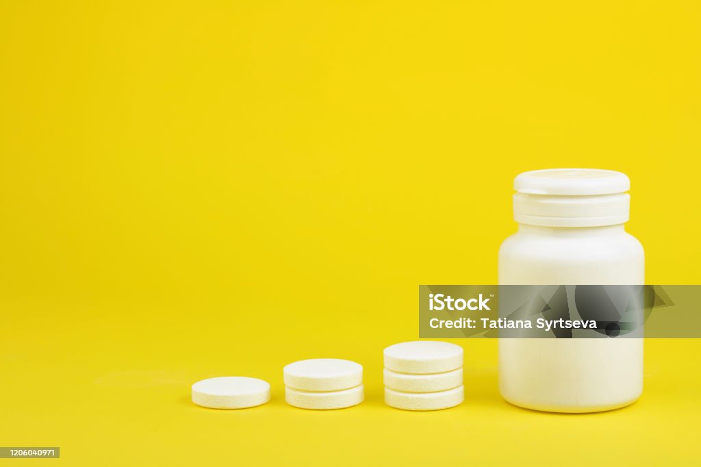 Comprimidos solúveis brancos perto da garrafa em um fundo amarelo. O remédio. Espaço de cópia - Foto de stock de Amarelo royalty-free Comprimidos solúveis brancos perto da garrafa em um fundo amarelo. O remédio. Espaço de cópia - Foto de stock de Amarelo royalty-free
