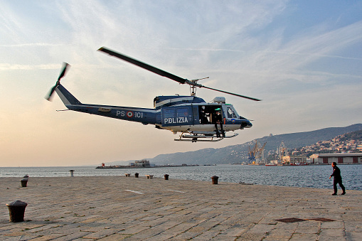 Trieste, Italy - September 27, 2009: Italian police helicopter with diver on the tailgate, during takeoff from the port dock.