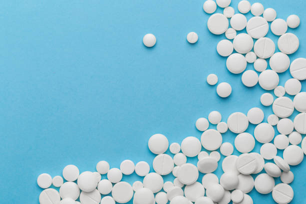 istock scattered white pills on a blue table. Layout for special offers such as advertising or other ideas. The concept of medicine, pharmacy and healthcare. Space for copy. 1206045780