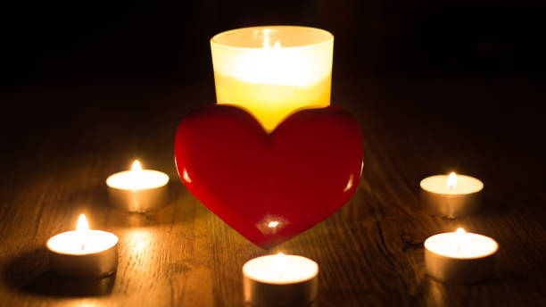 istock Christmas divination. Fortune telling. Divination for love. The red heart stands in the middle of the lighted candles. Ritual of love spell of the person. Postcard for Valentine's day or women's day 1206045892