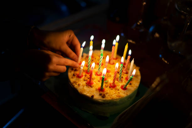 istock Hand placing candles on a birthday cake. 1206047322