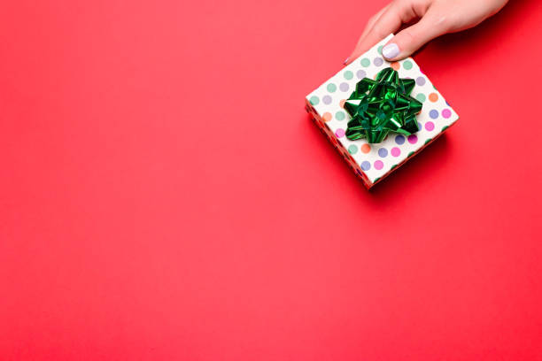 istock Woman holding gift box on red background, copyspace. Web banner, Valentine's Day greeting card, Mother's Day or Women's Day card in trendy colors, top view 1206050025