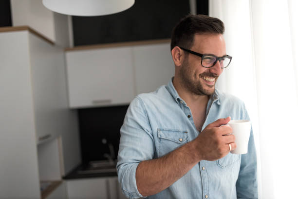 istock Happy handsome man drinking coffee in the morning looking through window 1206051535