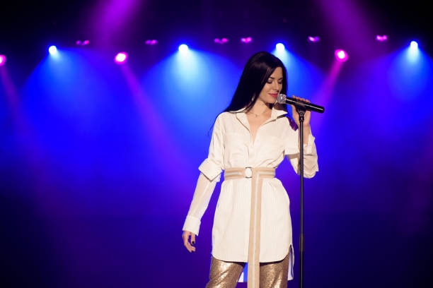 istock Cool singer with microphone on bright backlit stage in bright blue lights 1206052814