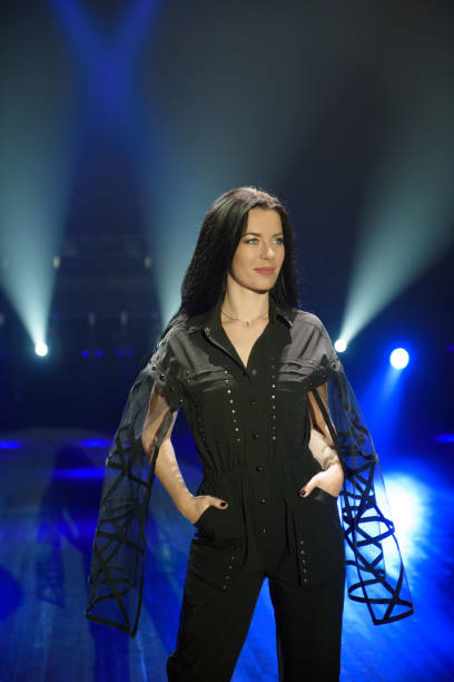 istock Girl in black suit performing on stage with bright blue background 1206052847