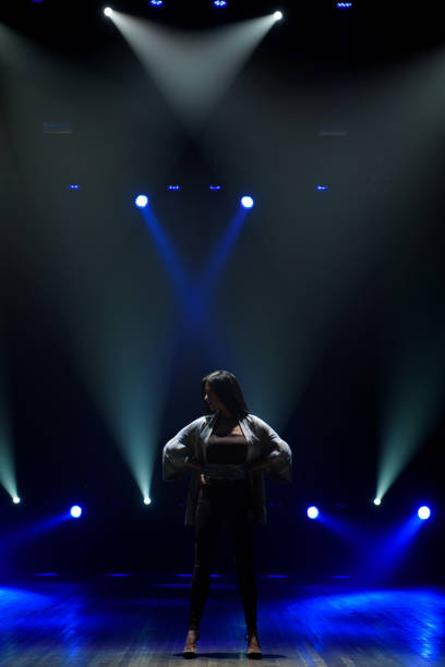 istock Girl in black suit performing on stage with bright blue background 1206052857