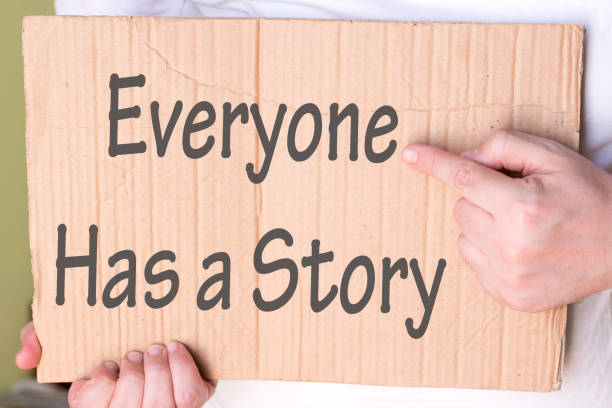 istock Everyone Has a Story Sign on cardboard. Man Hand Holding cardboard with text 1206055182