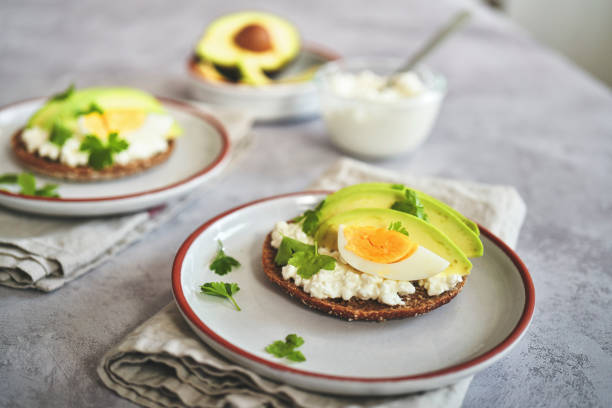 подготовка авокадо сэндвич с коричневым хлебом, творогом и яйцами - brown bread bread home interior food стоковые фото и изображения