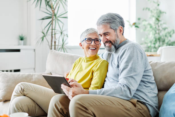 senior couple heureux tablette ordinateur amour ensemble - laptop sofa men computer photos et images de collection