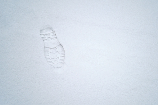 Man footprint on white winter snow. Track in snow. Flat lay overhead view. Snowy road. Winter footsteps background, copy space