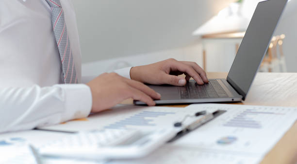 Marketers use computers to analyze documents and graphs of financial information about real estate investment budgets, Business men and tax concept.