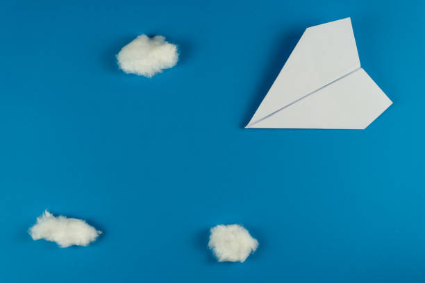 istock Handmade white paper plane on blue background with clouds made with cotton 1206068324