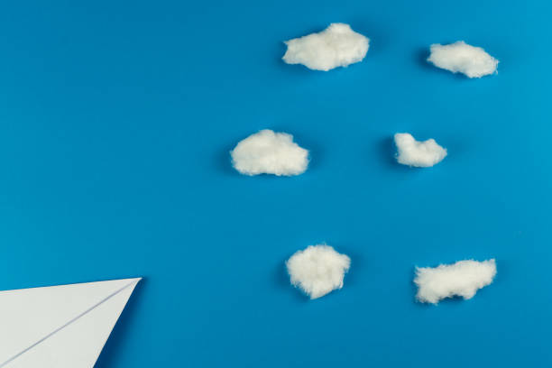 istock Handmade white paper plane on blue background with clouds made with cotton 1206068360