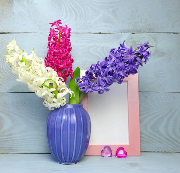 istock Three hyacinths: white, pink and violet in a ceramic violet vase, two glass hearts 1206068401