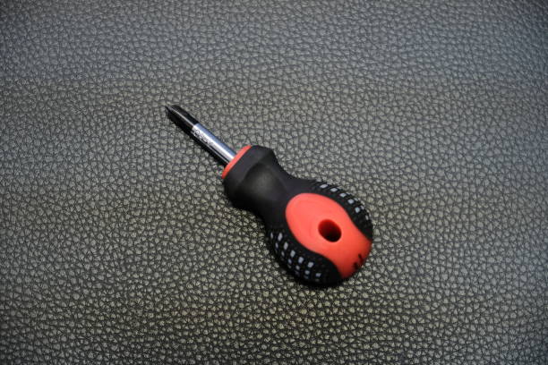 conducteur de vis à tête croisée court noir et rouge sur fond en cuir noir - screwdriver isolated phillips work tool photos et images de collection