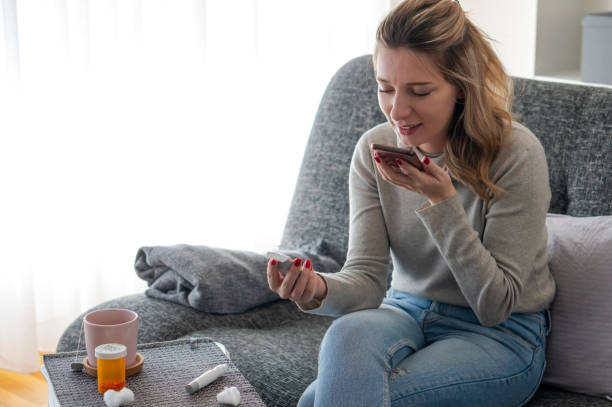 Young woman checking glucose level  and Video chatting With her Doctor at home stock photo