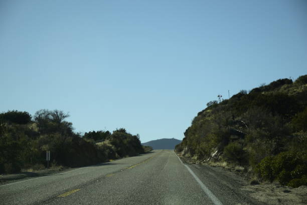 istock Empty Road Heading Up Hill Against Clear Blue Sky 1206071187