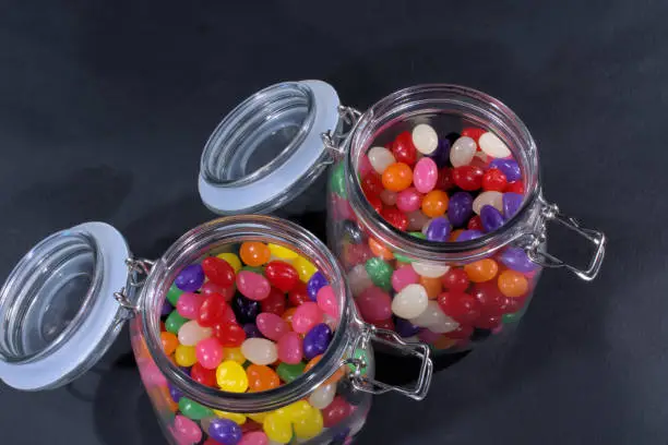 Open jars of jellybeans on a black background
