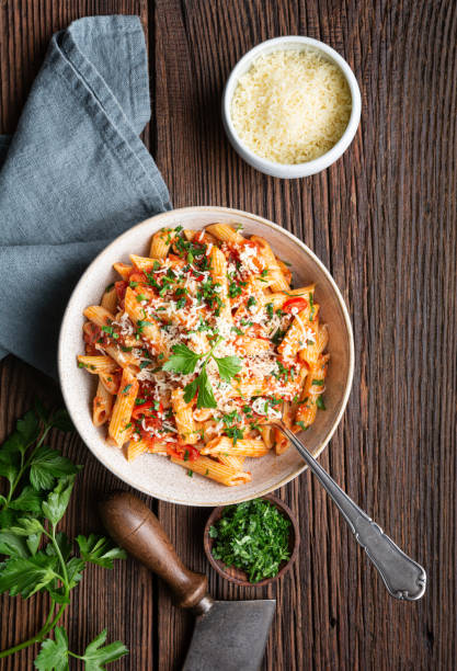 Classic penne all'Arrabbiata, spicy pasta with tomato and chilli sauce, topped with grated cheese stock photo
