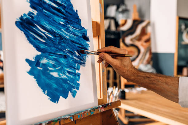 istock Hand of a painter holding a brush and drawing on canvas 1206083296